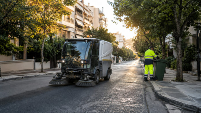 Δημοτικό σάρωθρο και εργαζόμενος καθαριότητας σε δεντροφυτεμένο δρόμο
