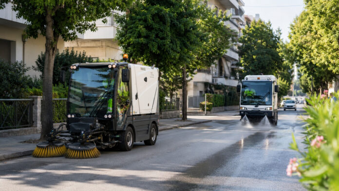 Δημοτικά οχήματα οδοκαθαρισμού σε δενδροφυτεμένο δρόμο προαστίου