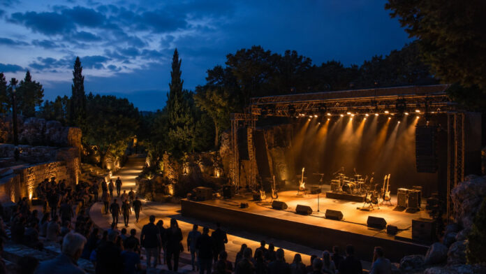 Φωτισμένη υπαίθρια σκηνή με κιθάρες και τύμπανα πριν από ροκ συναυλία
