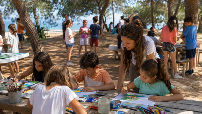 Παιδιά σε θερινή κατασκήνωση συμμετέχουν σε υπαίθρια δημιουργική δραστηριότητα