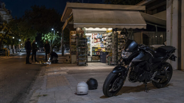 Μοτοσικλέτα και δύο κράνη έξω από αστικό περίπτερο κατά τη διάρκεια βραδινής έρευνας
