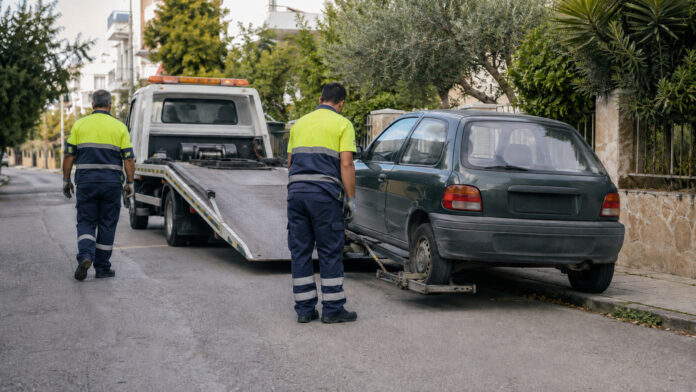 Συνεργείο προετοιμάζει παλαιό όχημα για μεταφορά με γερανοφόρο