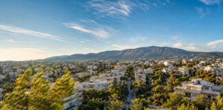 Αττική: Έως 35°C και 8 μποφόρ στα ανατολικά — η εικόνα στα βόρεια προάστια Ηλιόλουστη καλοκαιρινή εικόνα των βορείων προαστίων με δέντρα να κινούνται στον βοριά και την Πεντέλη στο βάθος