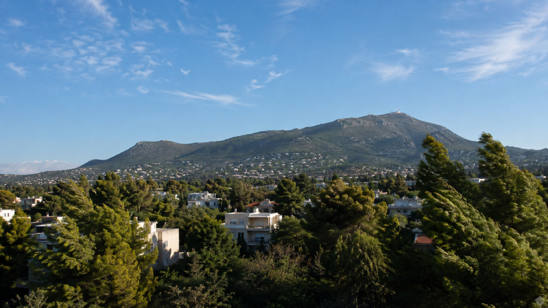 Ηλιόλουστη εικόνα των βορείων προαστίων και της Πεντέλης με δέντρα να λυγίζουν στον ισχυρό βοριά