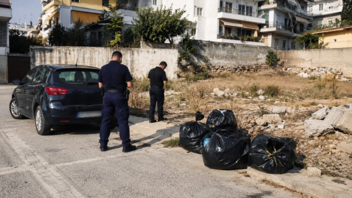 Αστυνομικοί πραγματοποιούν περιβαλλοντικό έλεγχο δίπλα σε σακούλες αποβλήτων σε αστική περιοχή