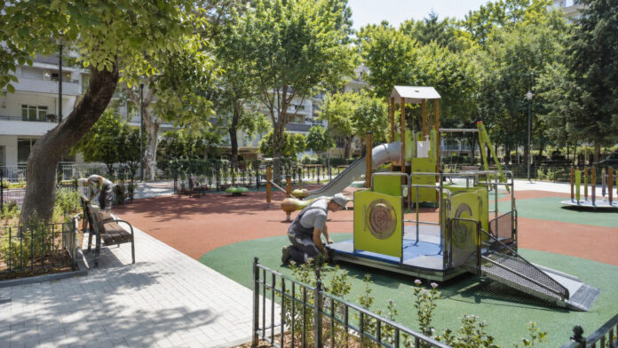 Σύγχρονη προσβάσιμη παιδική χαρά σε καταπράσινη αστική πλατεία