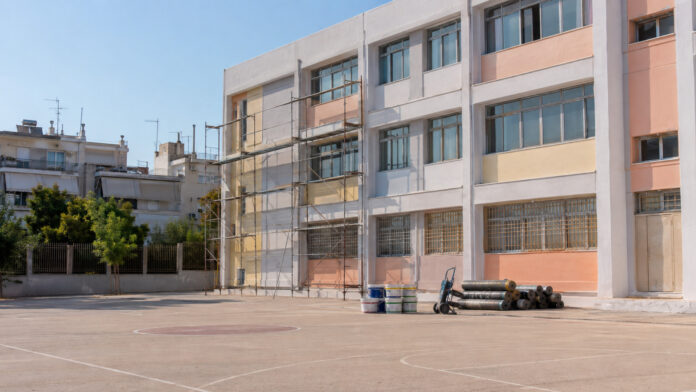 Σχολικό κτίριο με σκαλωσιές και υλικά συντήρησης δίπλα σε άδειο προαύλιο