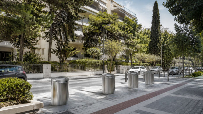 Σύγχρονοι υπόγειοι κάδοι απορριμμάτων σε καθαρό δεντροφυτεμένο αστικό δρόμο