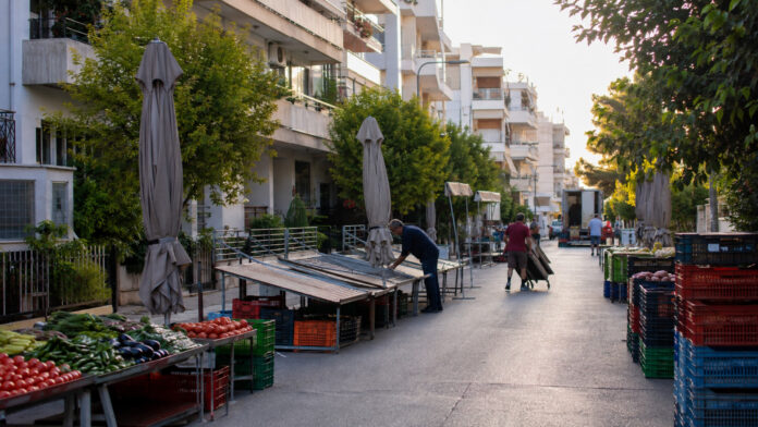 Πάγκοι και κιβώτια προϊόντων σε δρόμο που προετοιμάζεται για τη λειτουργία λαϊκής αγοράς