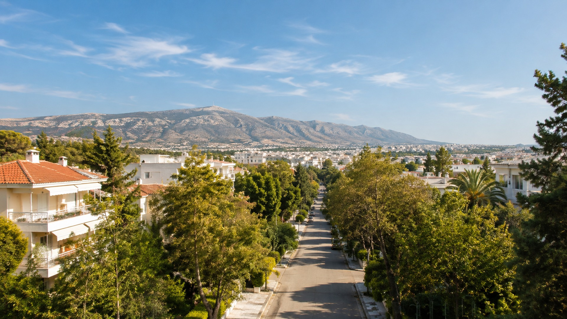 Ηλιόλουστη καταπράσινη γειτονιά των βορείων προαστίων με τον ορεινό όγκο της Πεντέλης στον ορίζοντα