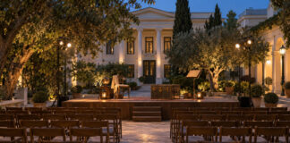 Κηφισιά: «Το Μόνον της Ζωής του Ταξείδιον» στα Μενάνδρεια Υπαίθρια θεατρική σκηνή σε φωτισμένο νεοκλασικό αίθριο με βιβλίο και παλιό ταξιδιωτικό μπαούλο