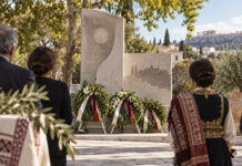 Νέα Ερυθραία: Τελετή μνήμης για τα θύματα της Μικρασιατικής Καταστροφής Στεφάνια και πολίτες μπροστά σε πέτρινο μνημείο σε δενδροφυτεμένη πλατεία