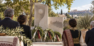 Νέα Ερυθραία: Τελετή μνήμης για τα θύματα της Μικρασιατικής Καταστροφής Στεφάνια και πολίτες μπροστά σε πέτρινο μνημείο σε δενδροφυτεμένη πλατεία