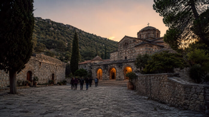 Βυζαντινός ναός σε ορεινό τοπίο με επισκέπτες στο προαύλιο