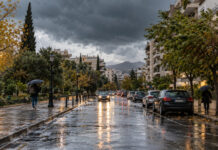Αττική: Ισχυρές βροχές και καταιγίδες την Τρίτη 13 Οκτωβρίου Βροχερός δρόμος σε αστική γειτονιά της Αττικής με πεζούς που κρατούν ομπρέλες