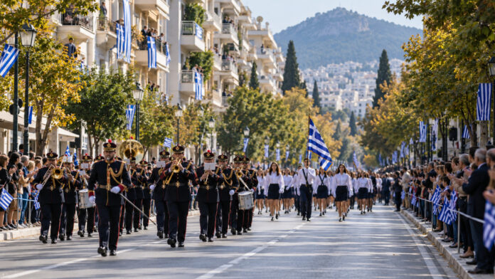 Αστική λεωφόρος προετοιμασμένη για επετειακή παρέλαση με ελληνικές σημαίες και φιλαρμονική